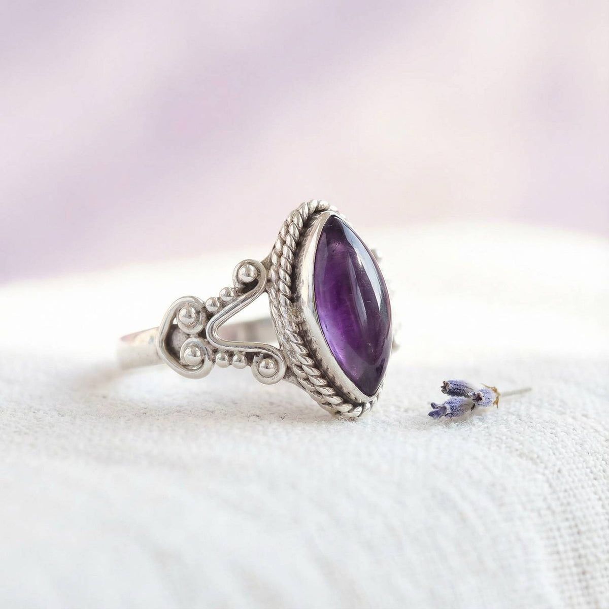 Silberring mit Amethyst auf hellem Stoff