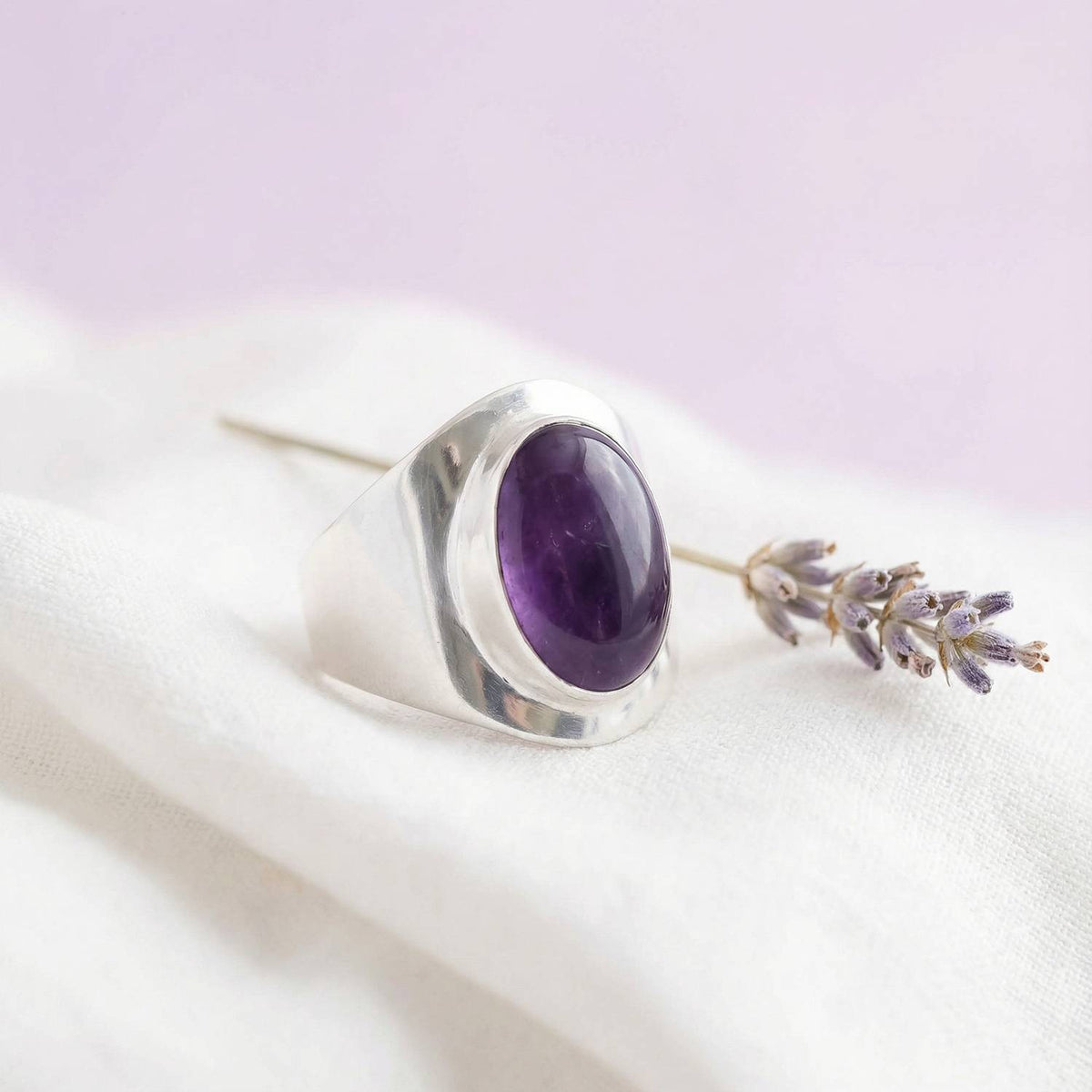 Silberring mit Amethyst auf hellem Stoff