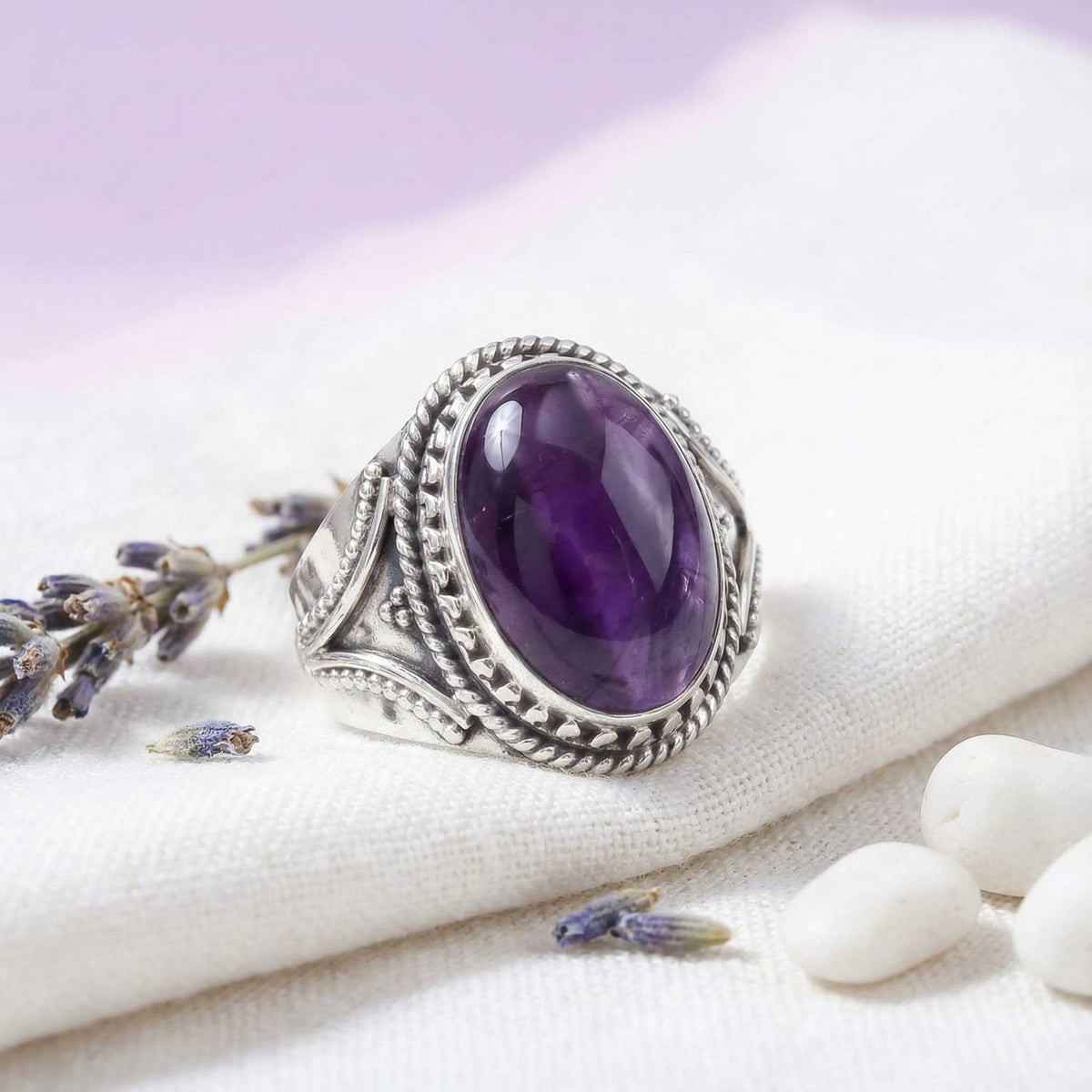 Silberring mit Amethyst auf hellem Stoff