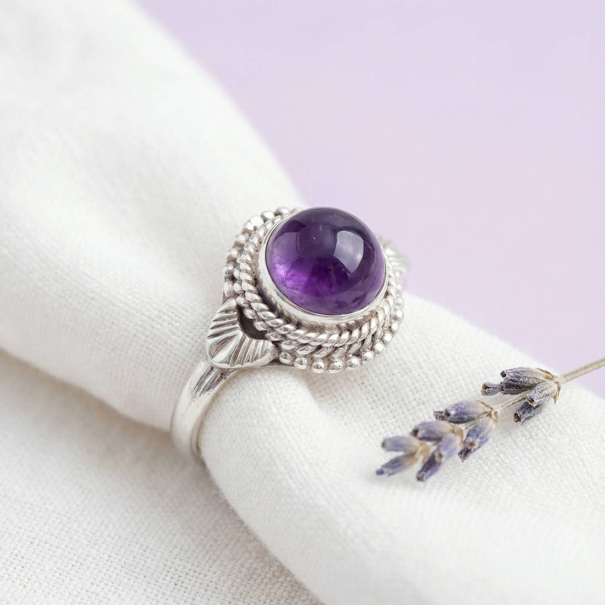 Silberring mit Amethyst auf hellem Stoff