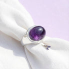 [KI] Silberring mit Amethyst auf hellem Stoff