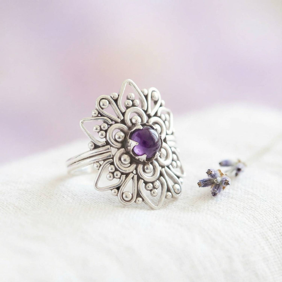 Silberring mit Amethyst auf hellem Stoff