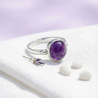 [KI] Silberring mit Amethyst auf hellem Stoff