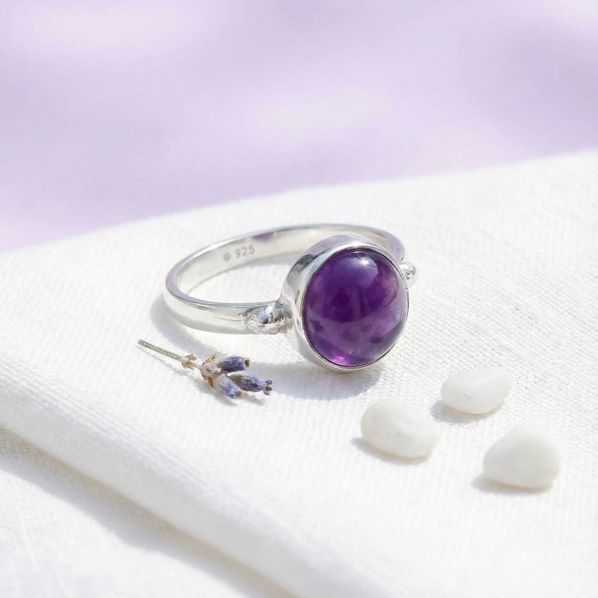 Silberring mit Amethyst auf hellem Stoff