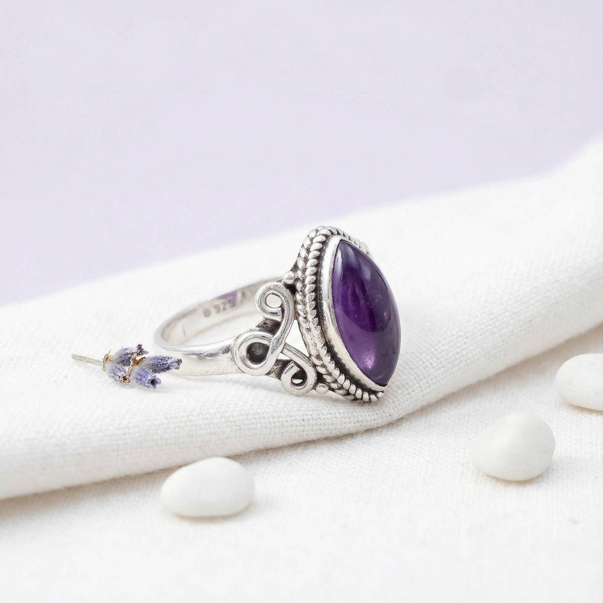 Silberring mit Amethyst auf hellem Stoff