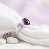 [KI] Silberring mit Amethyst auf hellem Stoff