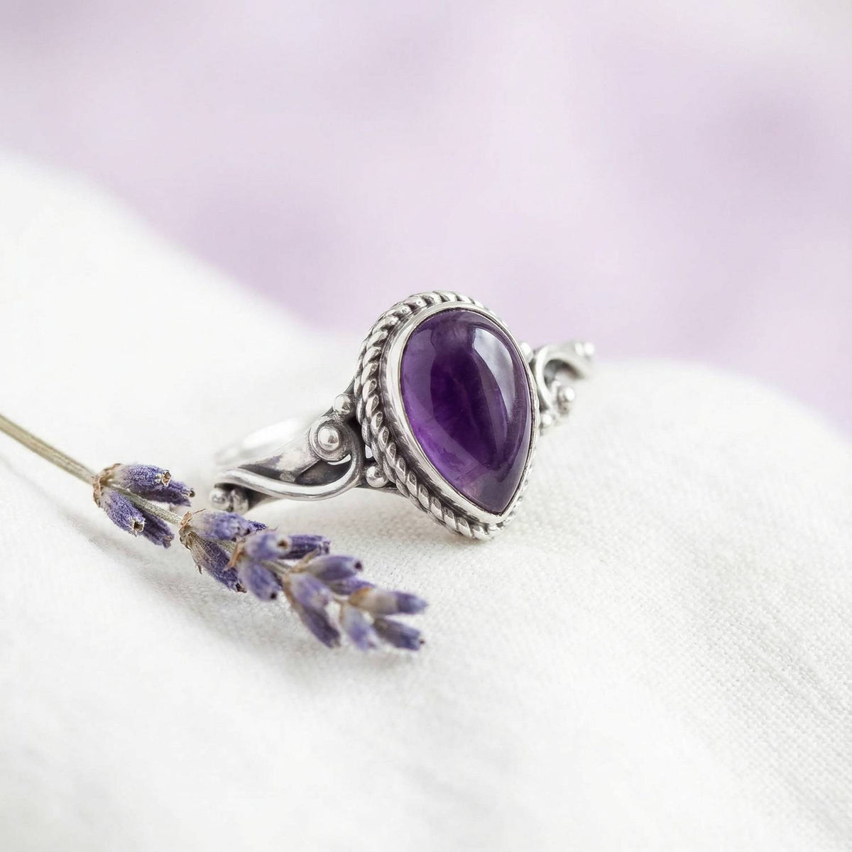 Silberring mit Amethyst auf hellem Stoff