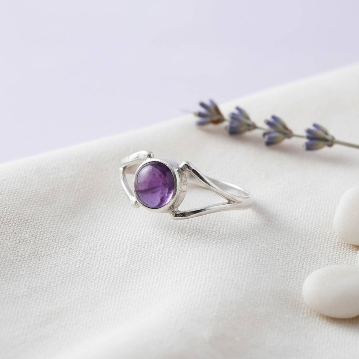 Silberring mit Amethyst auf hellem Stoff