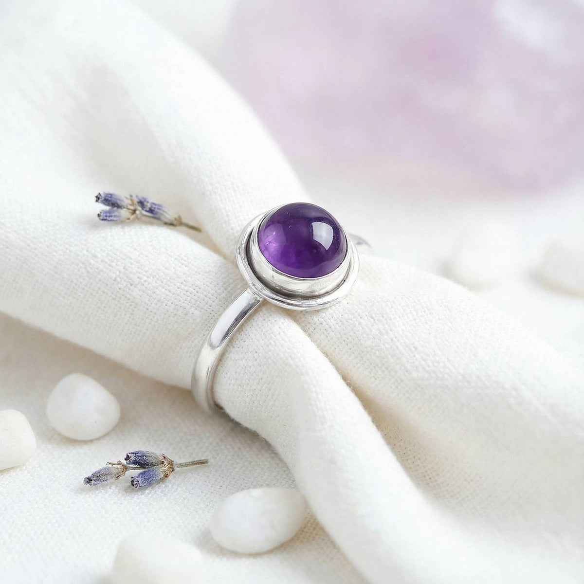 Silberring mit Amethyst auf hellem Stoff