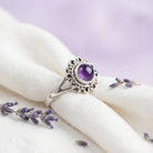 [KI] Silberring mit Amethyst auf hellem Stoff