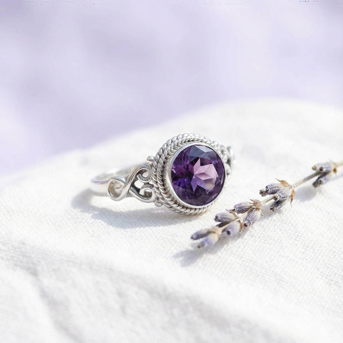 Silberring mit Amethyst auf hellem Stoff