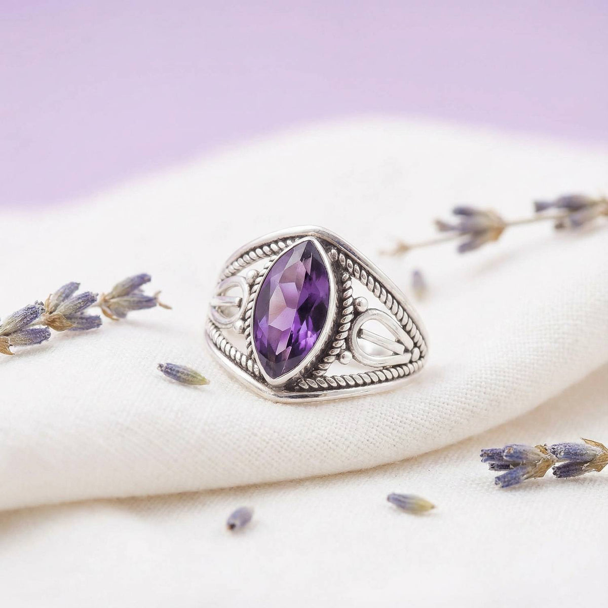 Silberring mit Amethyst auf hellem Stoff