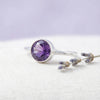 [KI] Silberring mit Amethyst auf hellem Stoff
