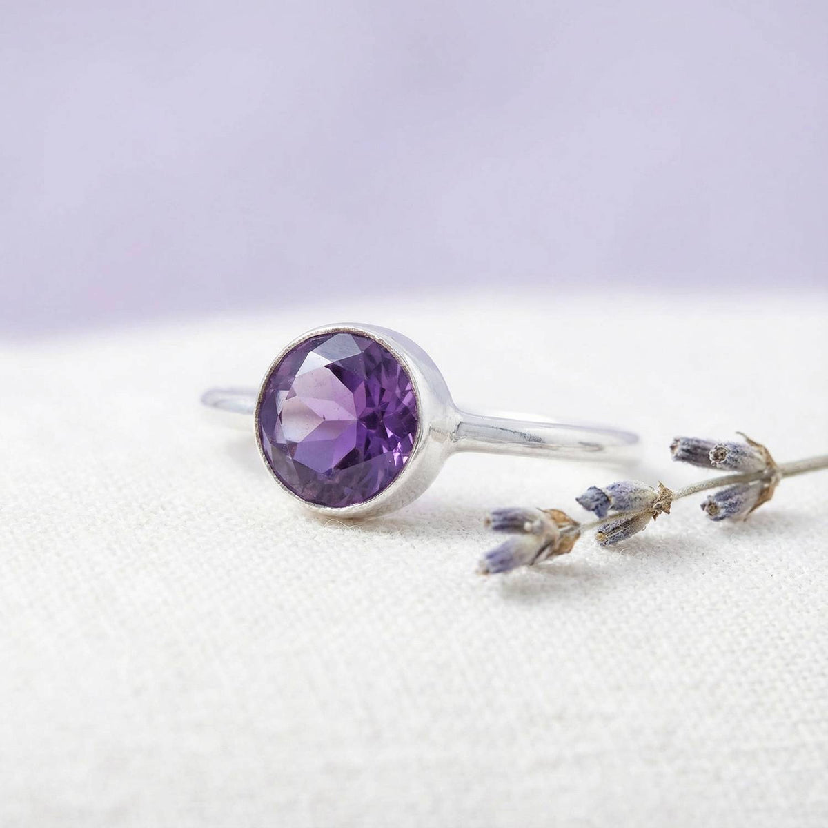 Silberring mit Amethyst auf hellem Stoff