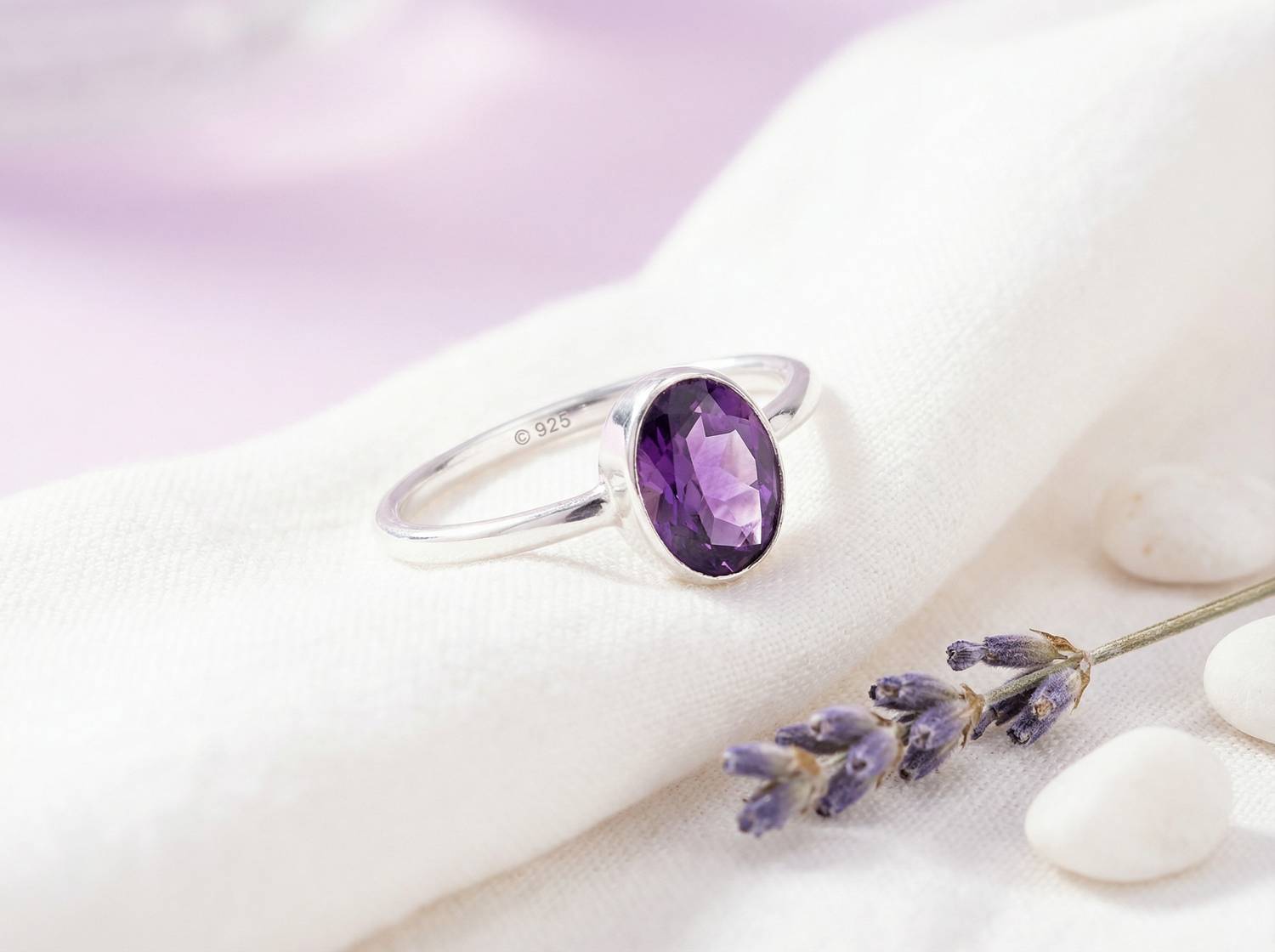 Silberring mit Amethyst auf hellem Stoff