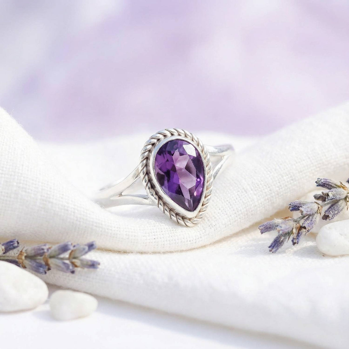 Silberring mit Amethyst auf hellem Stoff