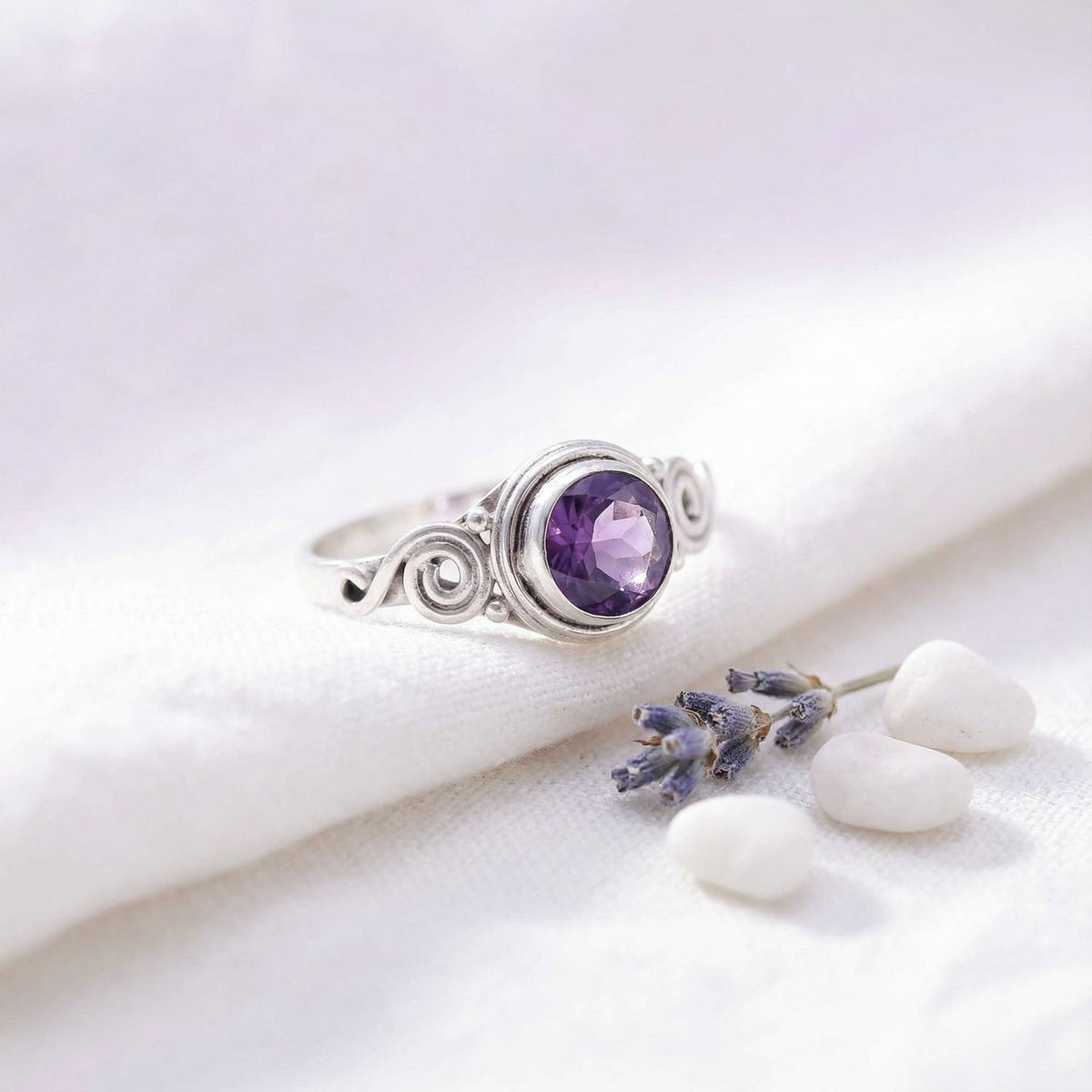 Silberring mit Amethyst auf hellem Stoff