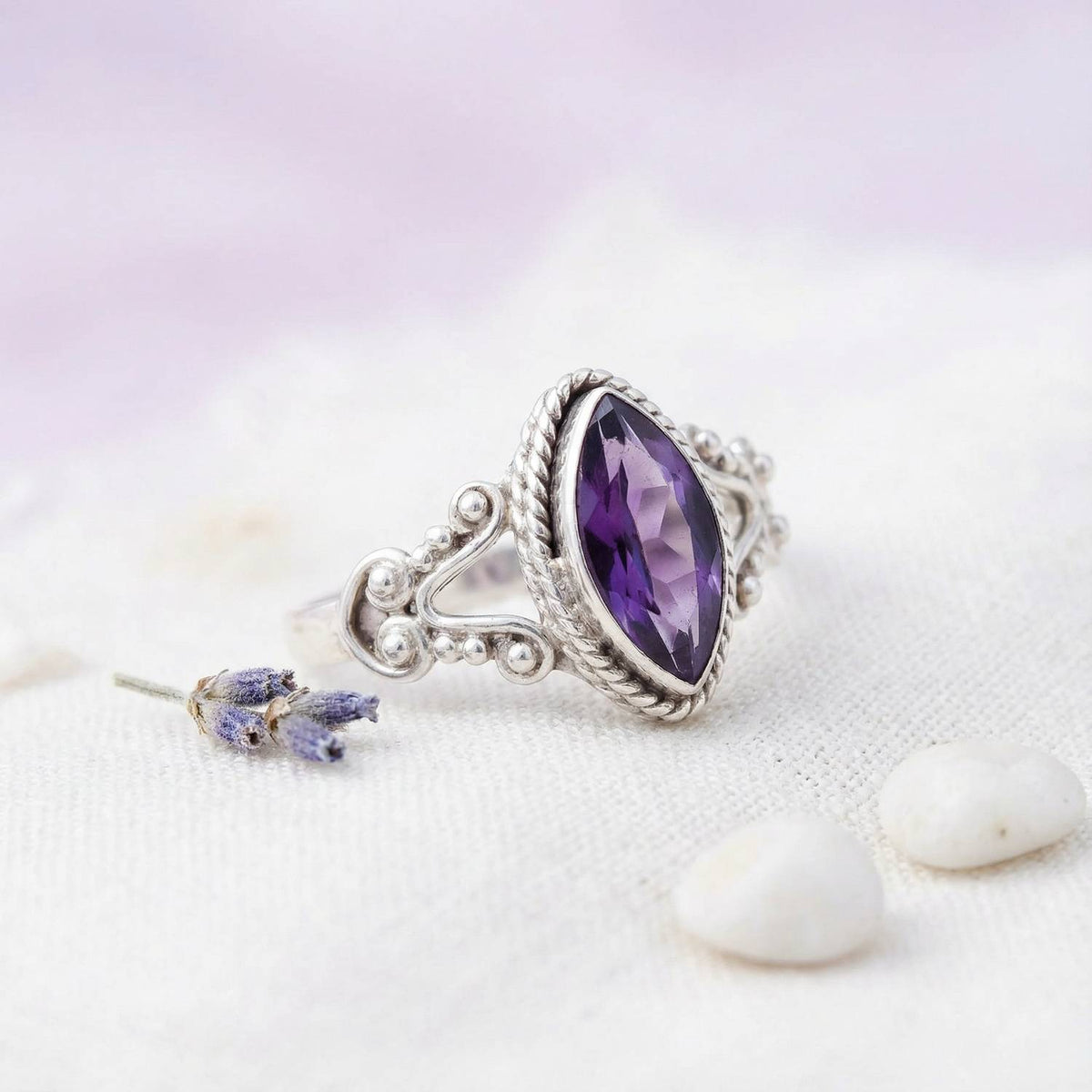 Silberring mit Amethyst auf hellem Stoff