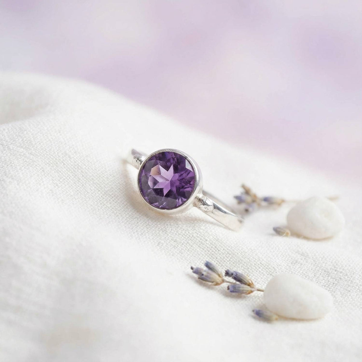 Silberring mit Amethyst auf hellem Stoff