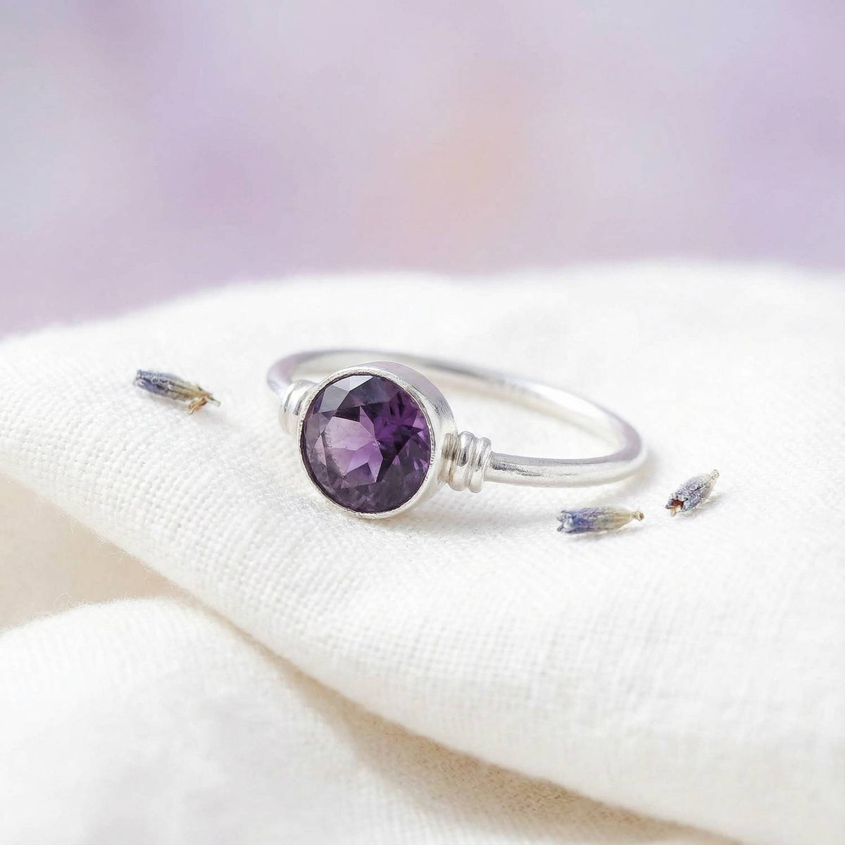 Silberring mit Amethyst auf hellem Stoff