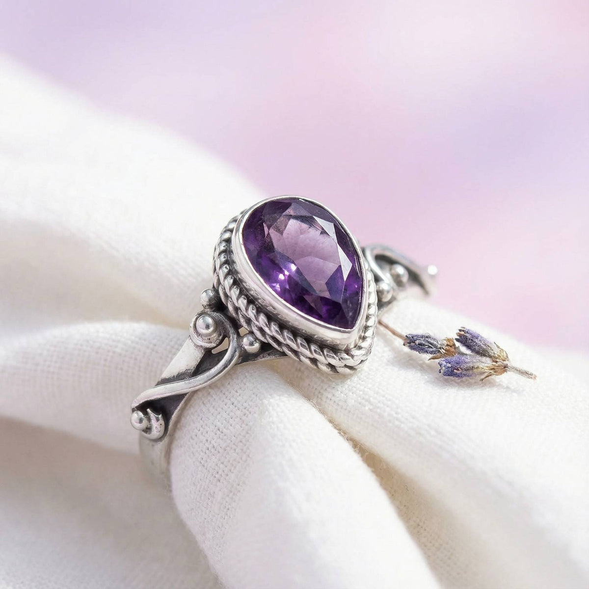 Silberring mit Amethyst auf hellem Stoff
