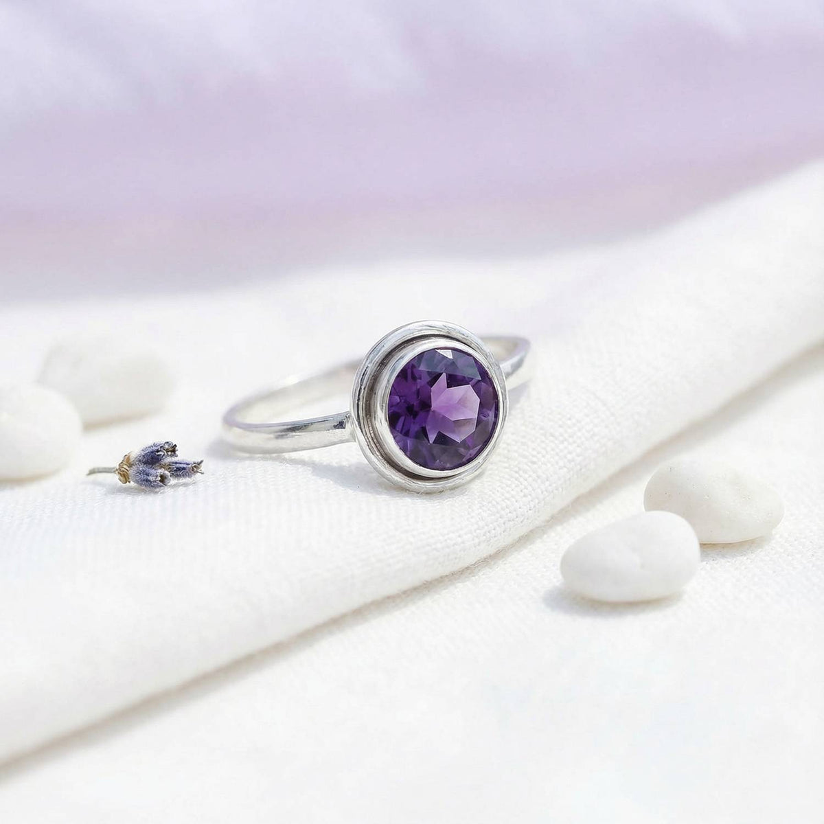Silberring mit Amethyst auf hellem Stoff