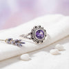 [KI] Silberring mit Amethyst auf hellem Stoff