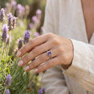 [KI] Silberring mit Amethyst an der Hand zwischen Blumen