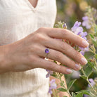[KI] Silberring mit Amethyst an der Hand zwischen Blumen