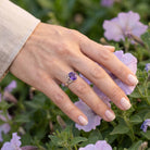 [KI] Silberring mit Amethyst an der Hand zwischen Blumen