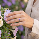 [KI] Silberring mit Amethyst an der Hand zwischen Blumen