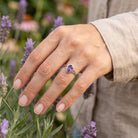[KI] Silberring mit Amethyst an der Hand zwischen Blumen