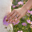 [KI] Silberring mit Amethyst an der Hand zwischen Blumen