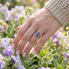 [KI] Silberring mit Amethyst an der Hand zwischen Blumen