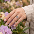 [KI] Silberring mit Amethyst an der Hand zwischen Blumen
