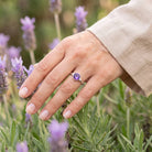 [KI] Silberring mit Amethyst an der Hand zwischen Blumen