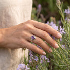 [KI] Silberring mit Amethyst an der Hand zwischen Blumen