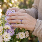 [KI] Silberring mit Amethyst an der Hand zwischen Blumen