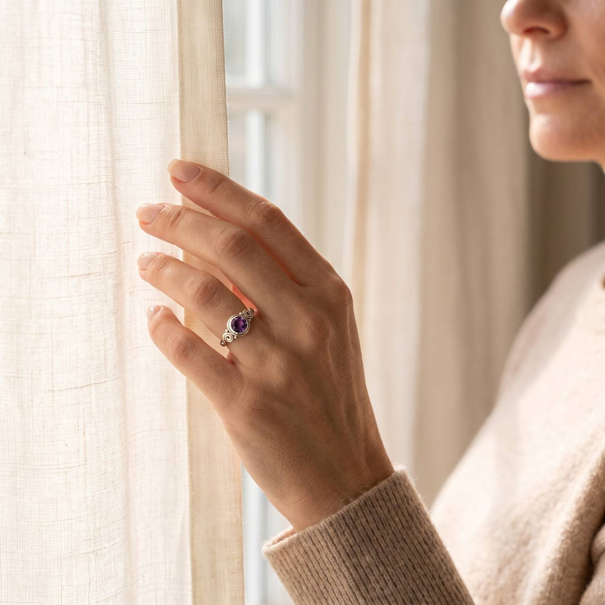 Frau trägt einen Amethystring aus Silber am Fenster