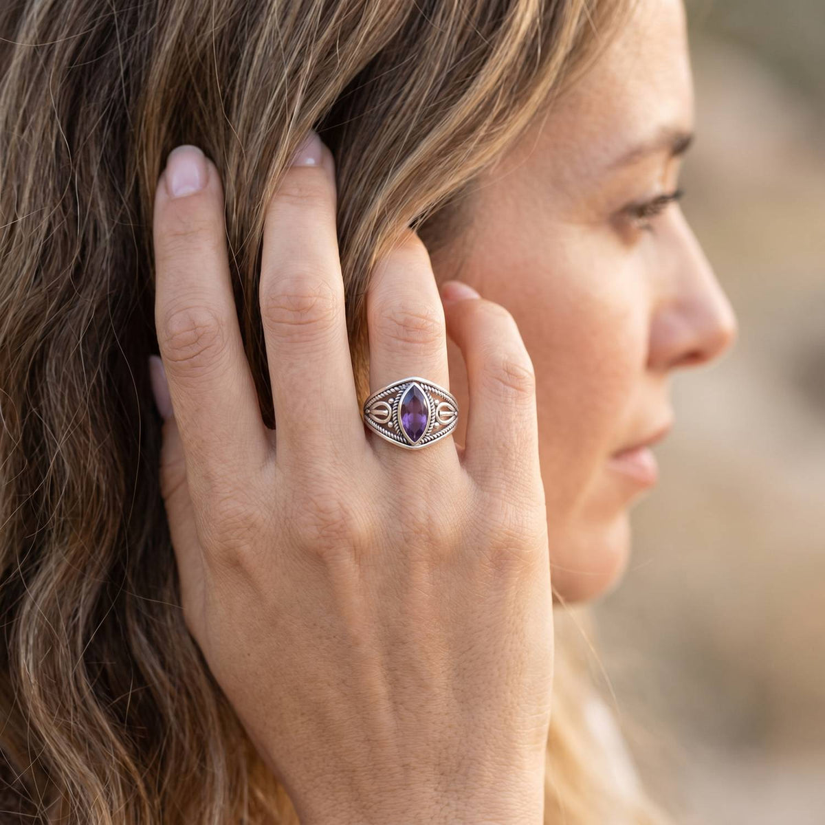 Frau trägt Silberring mit Amethyst an der Hand am Haar