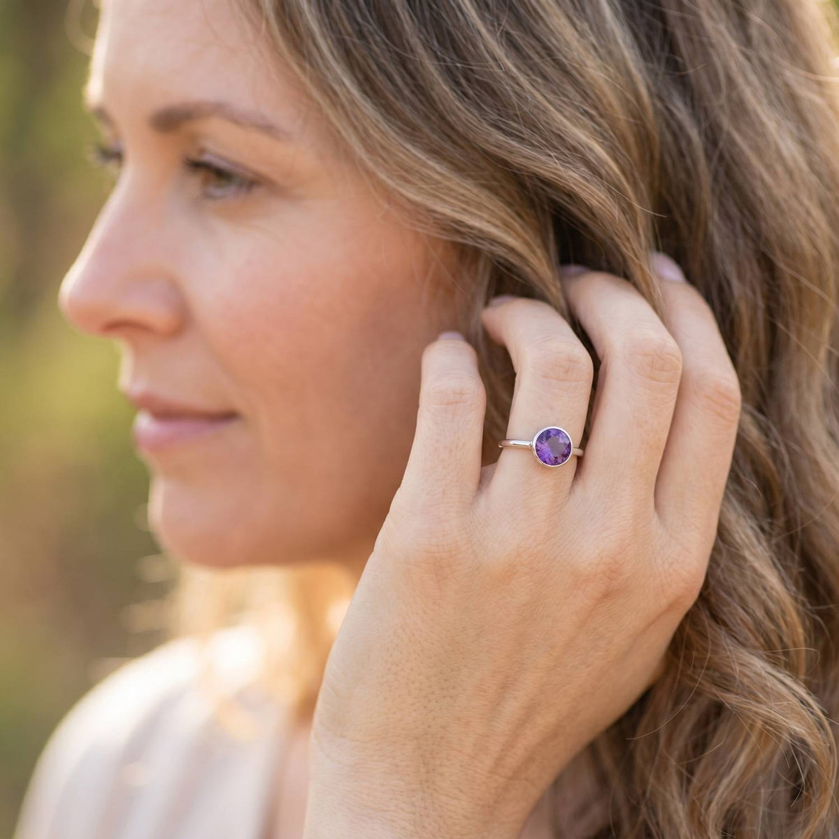 Frau trägt Silberring mit Amethyst an der Hand am Haar