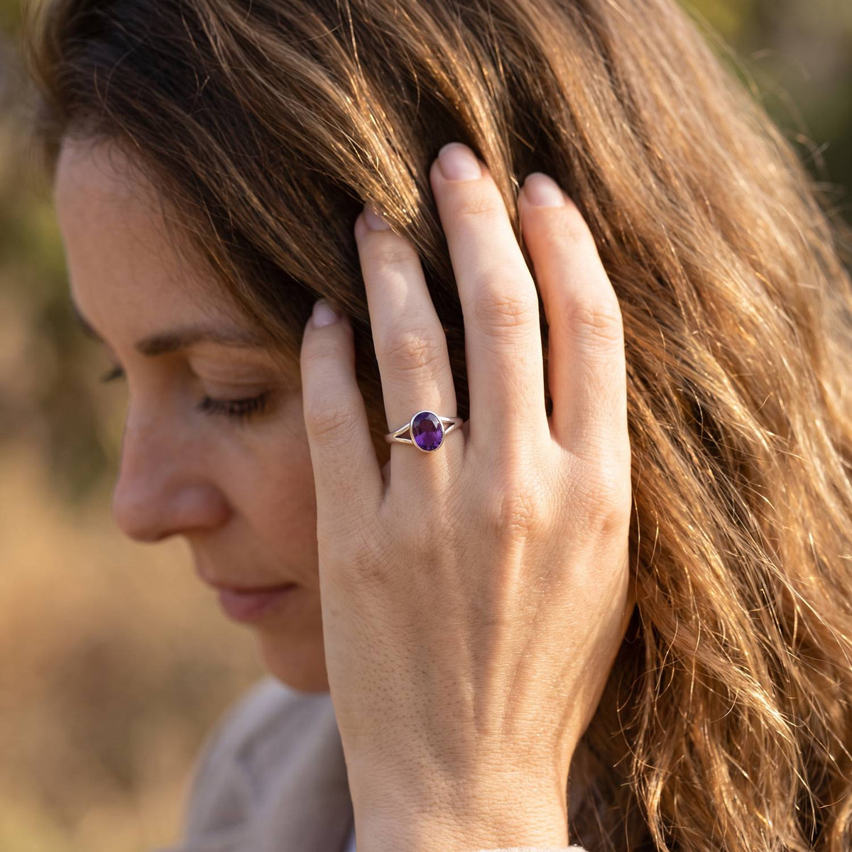 Frau trägt Silberring mit Amethyst an der Hand am Haar
