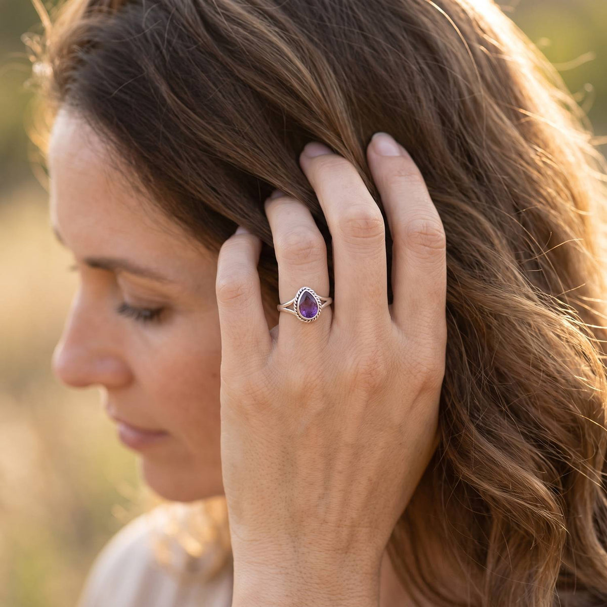 Frau trägt Silberring mit Amethyst an der Hand am Haar