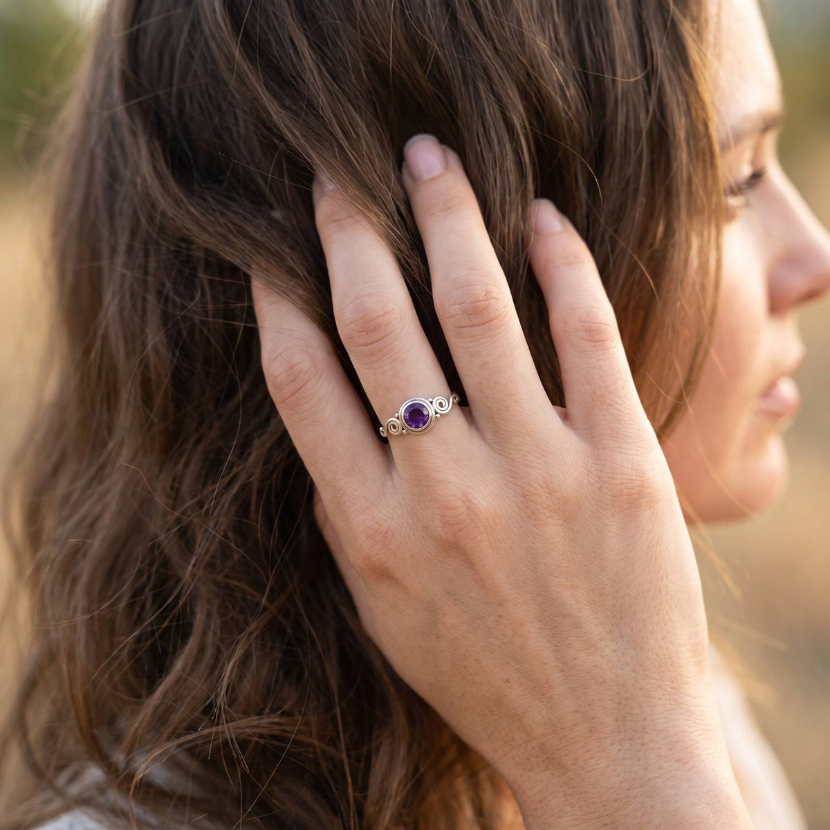 Frau trägt Silberring mit Amethyst an der Hand am Haar
