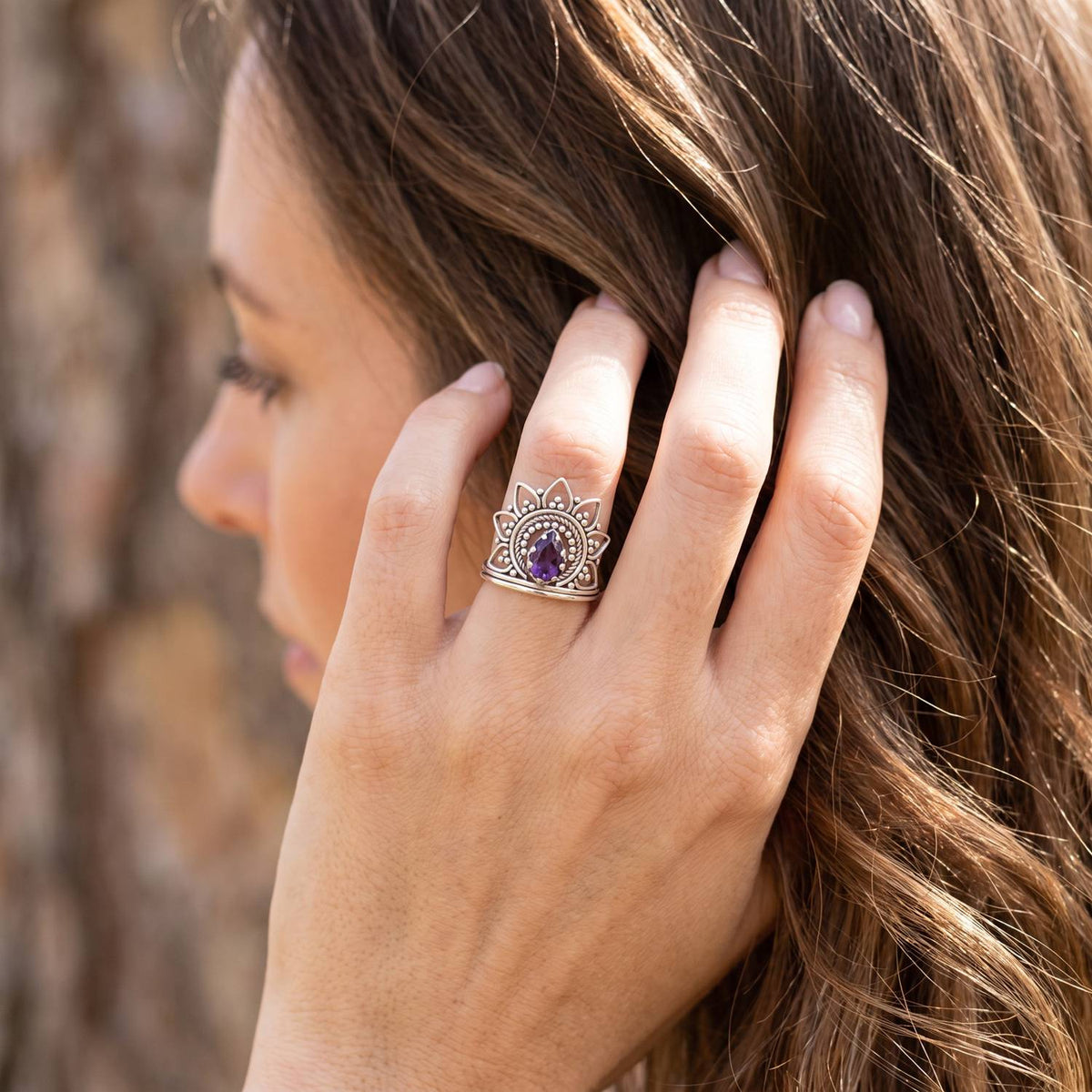 Frau trägt Silberring mit Amethyst an der Hand am Haar