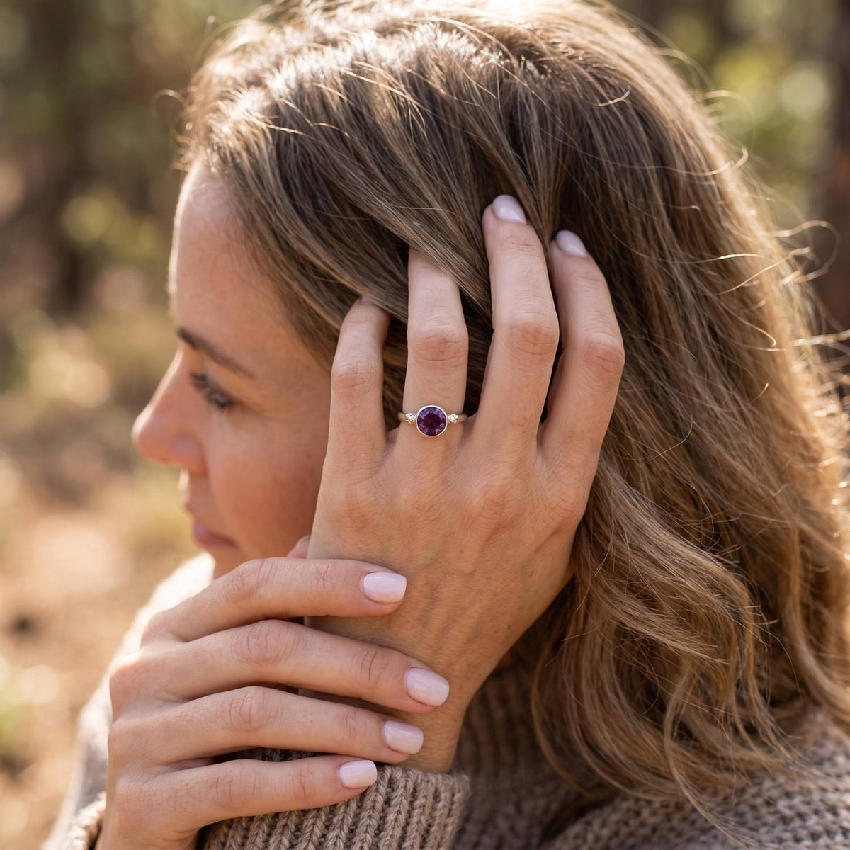 Frau trägt Silberring mit Amethyst an der Hand am Haar