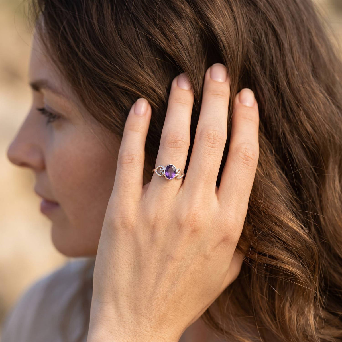 Frau trägt Silberring mit Amethyst an der Hand am Haar