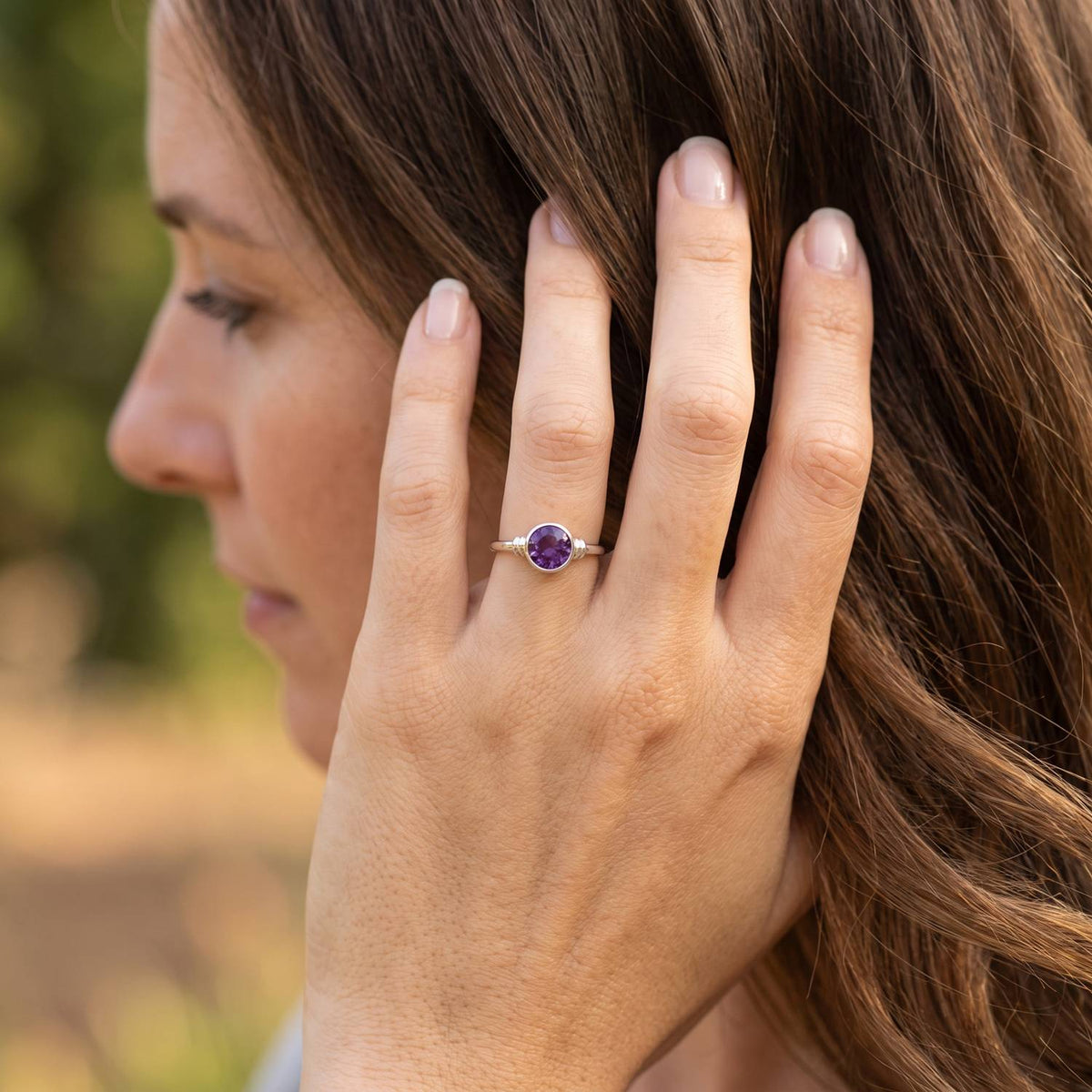 Frau trägt Silberring mit Amethyst an der Hand am Haar