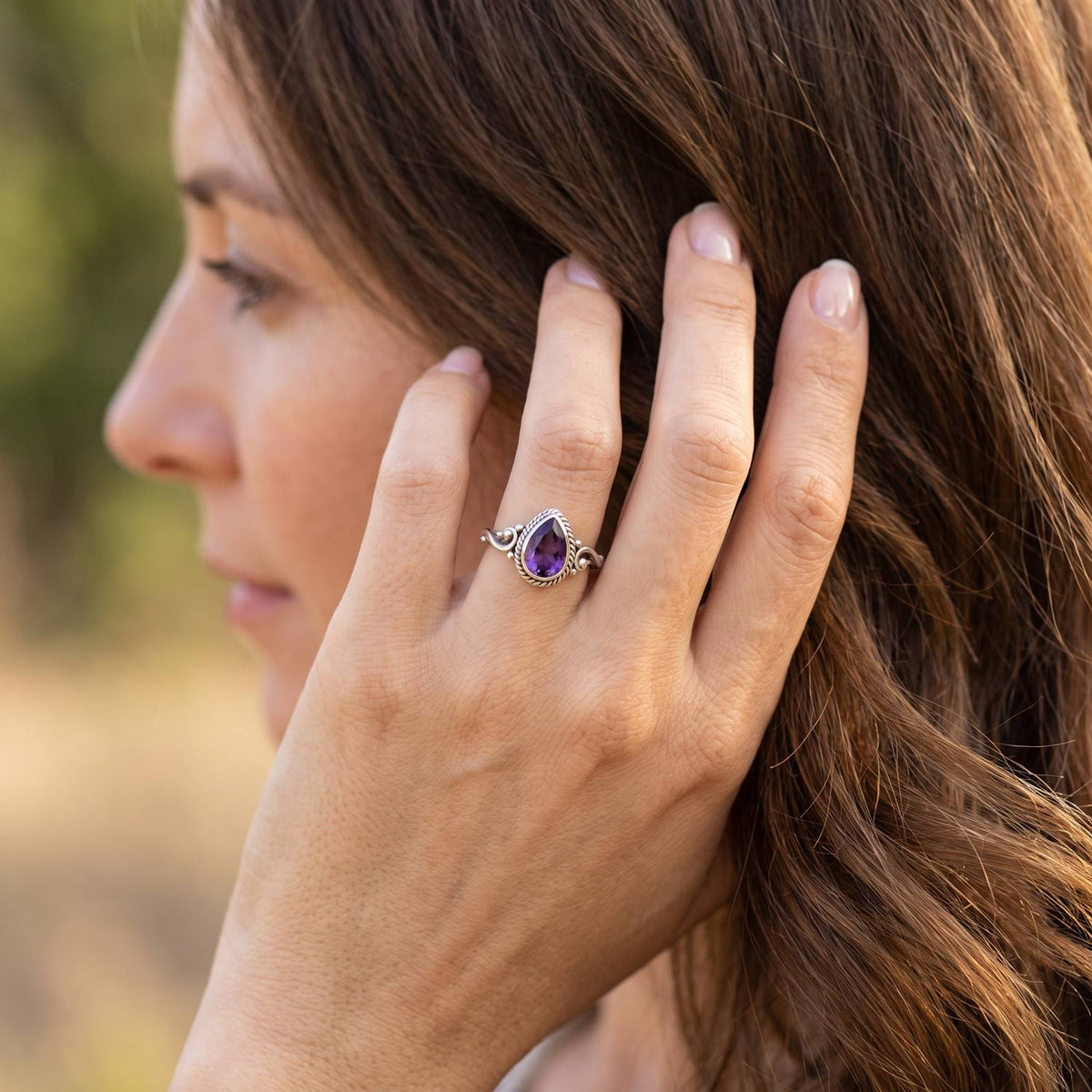 Frau trägt Silberring mit Amethyst an der Hand am Haar