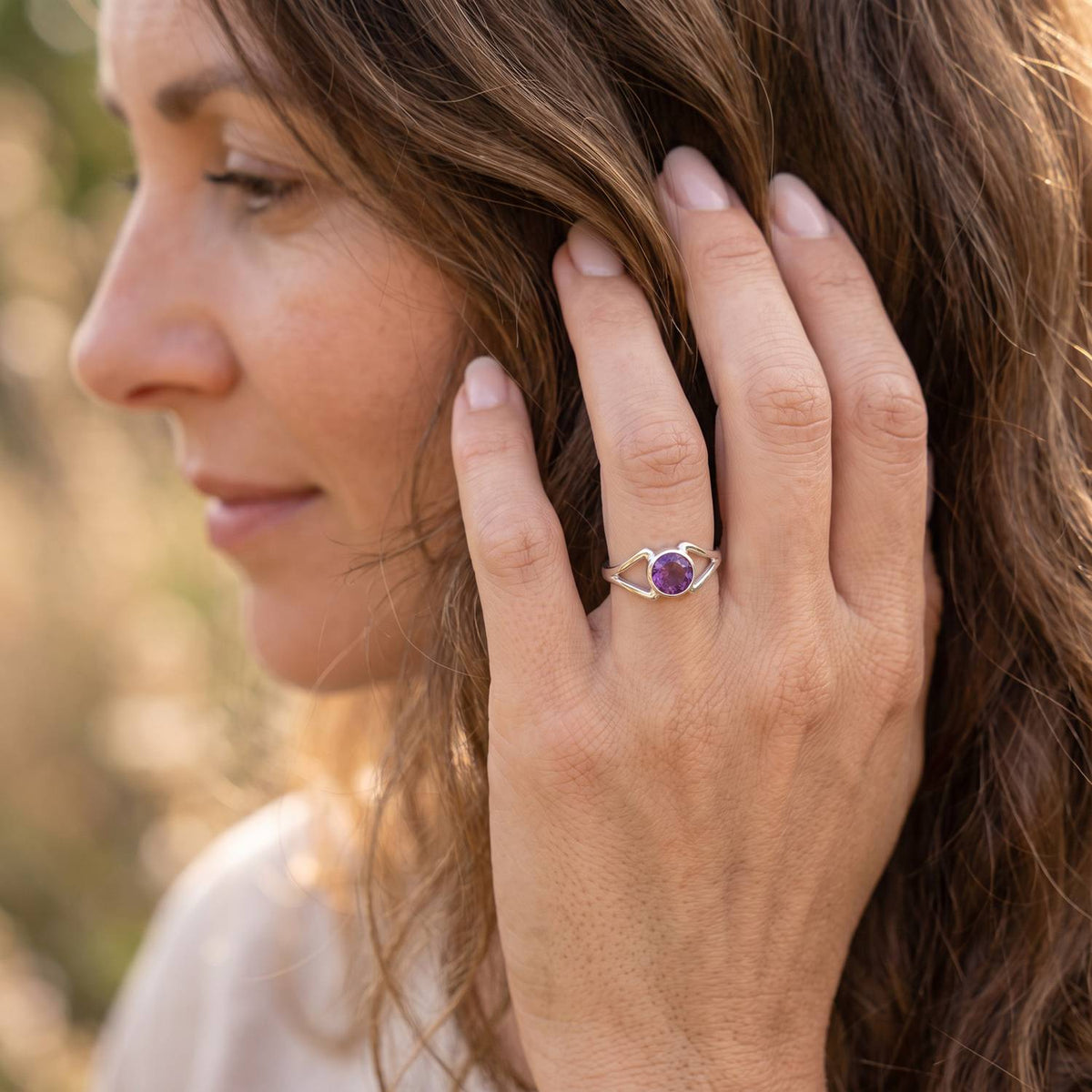 Frau trägt Silberring mit Amethyst an der Hand am Haar